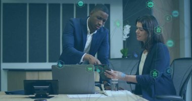 Toplantı masasında laptopun yanındaki tableti işaret eden takım elbiseli profesyoneller ellerinde belgeler var. İşbirliği, yenilik, üretkenlik, kurumsal, modern, takım çalışması, teknoloji