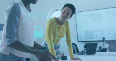 Ofis masasındaki belgeleri inceleyen iki iş kadını dizüstü bilgisayar ve holografik asma kilit kullanıyor. İşbirliği, takım çalışması, veri güvenliği, yenilik, profesyonel, modern, dijital