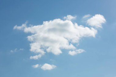 Tek kümülüs bulutu düz dizayn mavi gökyüzünde yüzüyor, ince bulutlarla çevrili. Minimalist, dingin, atmosferik, doğa, sükunet, havadar, neşeli