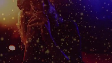 Şarkıcı mikrofon getiriyor ve turuncu mavi ışıklar altında şarkı söylüyor ve altın parçacıkları müzik için sürükleniyor. Performans, sahne, eğlence, canlı, etkileyici, yaratıcı, dinamik