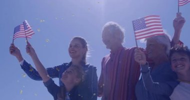 Aile mavi gökyüzünün altına adım atıyor, Amerikan bayrakları dalgalanan altın yıldız konfeti pazarlaması. Vatanseverlik, kutlama, birlik, çeşitlilik, mutluluk, açık hava, şenlik