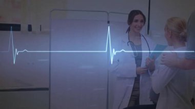 Doktor sonuçları açıklarken EKG çizgisi de destek veren arkadaşla sağlık danışmanlığında nabız yokluyor. Tıbbi, sağlık, profesyonellik, güvence, takım çalışması, klinik, tanı