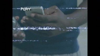 Mobil teknoloji kullanıcısı, VHS statik hatları akarken arkadaşından su şişesini su içmek için alıyor. Teknoloji, arkadaşlık, susuzluk, bağbozumu, gündelik, yaşam tarzı, iletişim