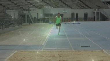 Erkek sporcu atletizm pistinde koşmaya başlıyor, kum havuzuna uzun atlama yapıyor. Sporcu, spor, fitness, yarışma, performans, antrenman, spor