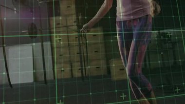 Atlama halatı tutan, fitness antrenmanı için sallanan yeşil ızgara izleme hareketi yapan bir kadın. Kardiyo, fitness, egzersiz, aktivite, güç, sağlık, spor salonu