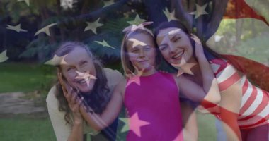 Anne ve çocuğu kucaklayan büyükanne pazarlamada çimlerin üzerinde bayrak şeklinde çimleri örtüyor. Aile, çok nesilli, portre, açık hava, doğa, sıcaklık, bağ.