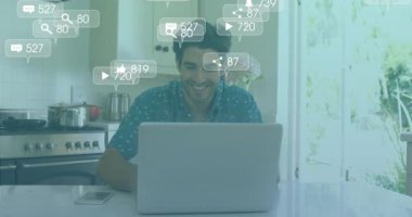 Adam mutfakta dizüstü bilgisayar açıyor ve akıllı telefonları dinlemeden önce yüzen sosyal medya uyarılarını izliyor. Teknoloji, modern, enerjik, yaşam tarzı, ev, dijital, bağlantı