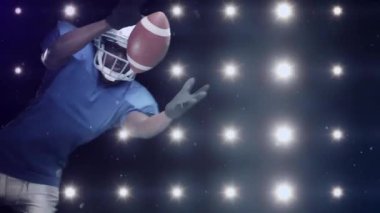 Futbol kasklı oyuncuya dönüşüyor. Yanıp sönen ışıklar arasında sıçrıyor ve topu güvene alıyor. Eylem, atletizm, stadyum, spor, rekabet, hareket, dinamik