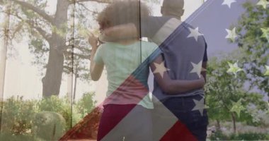 Bayrak örtüsü, çift olarak parkta yürürken sarılıyor ve kadınların seyahat için gözleri gölgede kalıyor. Romantik, dinginlik, ahenk, doğal, açık hava, boş zaman, arkadaşlık