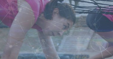 Takım arkadaşları engel parkurunda ip altında sürünüyorlar. Pembe bluz, tayt ve eldiven giyiyorlar. Macera, takım çalışması, azim, mücadele, fitness, açık hava, dinamik