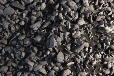 Düz tasarım, yoğun gri taşlar ve karanlık toprağı ince gölgelerle kaplayan çakıl taşlarını gösteriyor. Doku, doğal, engebeli, minimalist, toprak, açık hava, organik