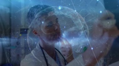 Doktor monitörlerden önce dönen holografik küreyi inceliyor ve analiz sırasında veri düğümlerini tıklatıyor. Sağlık, teknoloji, veri, görselleştirme, yenilik, tanı, bilim