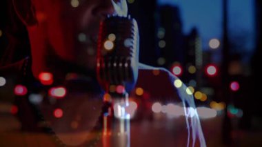 Erkek şarkıcı mikrofona eğiliyor, müzik stüdyosunda sürüklenen şehir bokeh 'i ile şarkı söylüyor. Performans, vokal, gece hayatı, caz, sanatçılık, ambians, mikrofon