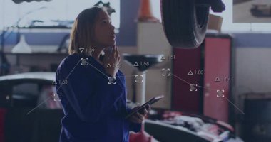 Kadın otomobil teknisyeni elinde tablet tutarak kaldırılan lastikleri kontrol ediyor ve teftiş verilerini giriyordu. Tamirci, otomotiv, alet çantası, teknik, endüstri, onarım, teşhis