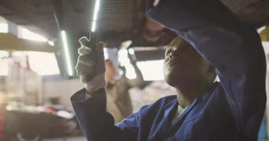 Tamirci LED lambayı açıyor ve otomatik onarım için animasyon mercek fişekleri ile şasiye tarama yapıyor. Otomotiv, onarım, endüstri, teknisyen, aydınlatma, teftiş, atölye