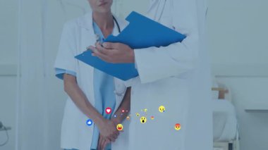 Hemşire yüzen emojilerle başını sallarken doktor hasta notlarını inceliyor. Tıbbi, sağlık, klinik, profesyonel, teşhis, takım çalışması, modern