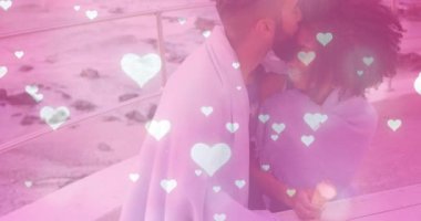 Bir erkek, romantik pazarlamayı ön plana çıkaran animasyon kalplerle öpüşürken, kürsüde bir kadına yaslanıyor. Şefkat, samimiyet, deniz kenarı, şefkat, arkadaşlık, bağlantı, romantizm