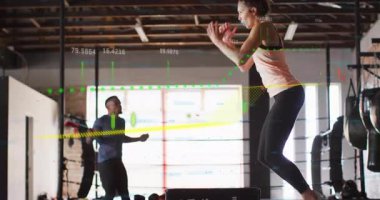 Spor salonunda dizlerini büküp kutuya atlayan kadın sporcu, ölçüm aletleriyle ip atlayan erkek gibi. Fitness, atletik, antrenman, egzersiz, dinamik, performans, sağlık