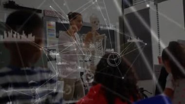 İskeleti kavrayan ve kafatasını döndüren sonra da ağ kaplamalı sınıfa anatomi öğreten eğitmen. Eğitmen, öğrenme, eğitim, bilim, sınıf, öğretim, katılım