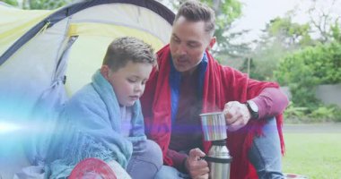 Baba, oğlunun ısınması ve sağlıklı bir bağ kurması için çaydanlığı kaldırıyor ve sıcak içeceği döküyor. Macera, kaynaşma, sıcaklık, açık hava, doğa, eğlence, aile.