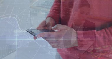 Akıllı telefonu tutan, kırmızı kazaklı bir adam masasında veri örtüleriyle piyasa haritalarını analiz ediyor. Finansal, teknoloji, dijital, analitik, profesyonel, ticari, veri görselleştirmesi