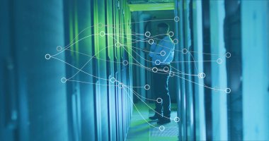 Beyaz gömlekli bilişim teknisyeni sunucu odasındaki sunucu dolaplarını LED ağ kaplamalı olarak inceliyor. Teknoloji, veri, siber güvenlik, altyapı, yenilik, dijital, ağ