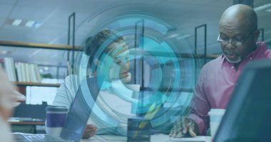 Takım elbiseli iki meslektaş ofis masasında dizüstü bilgisayarlı ve dijital kaplamalı belgeleri inceliyor. İşbirliği, yenilik, teknoloji, iş, profesyonellik, takım çalışması, strateji