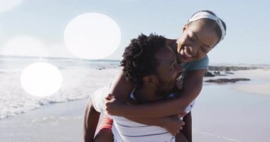 Kadının omuzlarına binen erkek, plaj turizmini çift etrafında yanıp sönen lenslerle başlatıyor. Romantizm, sahil, açık hava, mutluluk, eğlence, yaşam tarzı, eğlence