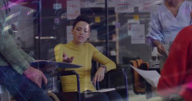 Tekerlekli sandalyedeki iş kadını belgeleri alıyor ve planlama için animasyon çizelgeleriyle gözden geçiriyor. İşbirliği, takım çalışması, profesyonellik, kapsama, engellilik, çeşitlilik, şirket