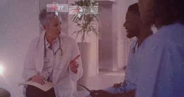 Kıdemli doktor hasta notlarını akran sorgulama tableti olarak göstererek uyarı simgelerinin kaybolmasına neden oluyor. Tıbbi ekip, işbirliği, iletişim, dijital sağlık, sağlık teknolojisi, klinik tartışma, mesleki çevre