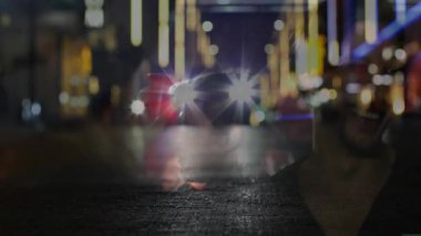 Pazarlama farlarını yakalıyor erkek, ışığı yakalamak için kırmızı bardağa doğru dönüyor. Şehir, gece hayatı, neon, yansıma, arkadaşlık, karamsar, canlı