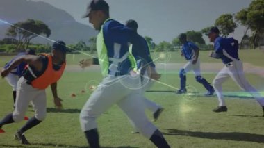 Koç takım arkadaşlarına beysbol antrenmanında koşuya, geri vitese takıp kırmızı konileri atlamalarına işaret ediyor. Eğitim, performans, koçluk, atletizm, takım çalışması, dinamik, hareket