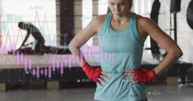 Kadın yoğun antrenmanı bitiriyor, spor salonunda duraklıyor, grafikler izleme uygunluk ölçümlerini güncelliyor. Fitness, biyomekanik, veri görselleştirme, güç, atletizm, yüksek teknoloji, aktif yaşam tarzı