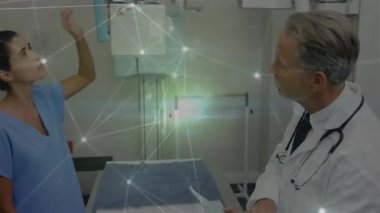 Tıbbi tarama için teknisyen paneli ve X-ray tüpü kolunu hareket ettirirken doktor çizelgeyi gözden geçirir. Radyoloji, sağlık, klinik, profesyonel, tanı, hastane, ekipman