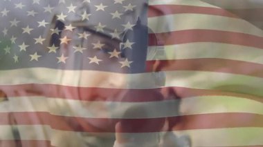 Amerikan bayrağı, ormanın savaşında tüfeği destekleyen askerin üzerinde. Atış için tam yol gösterici. Askeri, eğitim, hassasiyet, taktik, vatanseverlik, kamuflaj, strateji