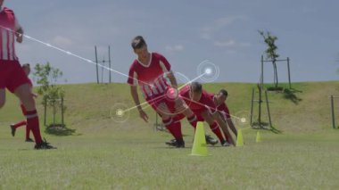 Futbol talimi oyuncuları yakalıyor. Düdük sesiyle koşuyorlar. İz sürme konileri ile çeviklik konilerini geziyorlar. Sporcular, antrenman, hareket, spor giyim, spor, teknoloji, açık hava