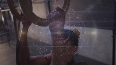 Yüzükleri tutan orta yaşlı bir kadın, sağlık için çeken, kafasının etrafında titreşen saydam dünya animasyonu. Güç, zindelik, kararlılık, teknoloji, atletizm, refah, yenilik