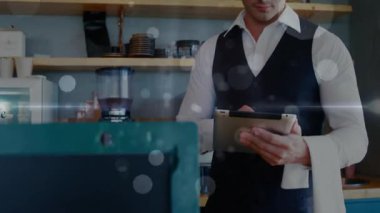 Kahve siparişlerini onaylamak için tableti tıklatıyor, sonra da yüzen ışıkların arasında bakıp gülümsüyor. Müşteri hizmetleri, dijital teknoloji, modern tasarım, konukseverlik endüstrisi, profesyonel kıyafetler, sıcak atmosfer, personel etkileşimi