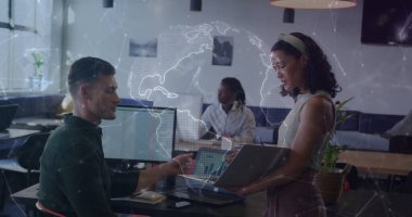 Bilgisayarı tutan ve açık planlı ofiste dijital dünya haritasıyla yazı yazan iş arkadaşları. İşbirliği, teknoloji, yenilik, takım çalışması, modern, profesyonel, dijital