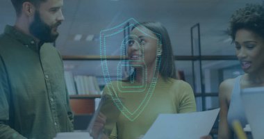 Ofisteki masada tablet, dizüstü bilgisayar ve dijital kalkanla belgeleri inceleyen üç profesyonel. İş, işbirliği, teknoloji, yenilik, veri güvenliği, çalışma alanı, modern