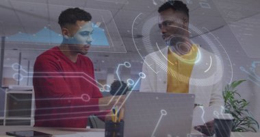 Kırmızı tişörtlü jestçi şirket ofisindeki tablet üzerinde laptop ve kahve fincanı ile veri sunuyor. İşbirliği, teknoloji, modernite, analitik, iletişim, yenilik, çalışma alanı