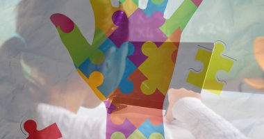 Beyaz süveter giyen Çinli bir kız, beyaz masadaki tableti renkli bulmacalarla örtüyor. Çocuklar, eğitim, yaratıcılık, teknoloji, yenilik, öğrenme, dijital