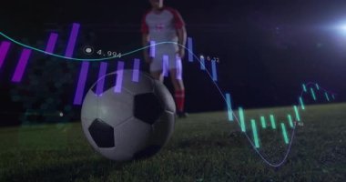 Erkek oyuncu, futbol topuna doğru koşmaya başlıyor. Sel ışığında istatistikleri analiz ederek atış yapıyor. Sporcu, hareket, spor, gece vakti, teknoloji, performans, stadyum