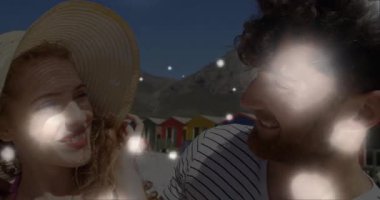 Şapka ayarlayan kadın, plajda seyahat pazarlaması için gülümseyen bir çift olarak ışıldıyor. Romantizm, açık hava, eğlence, coşku, huzur, manzara, bağlantı.