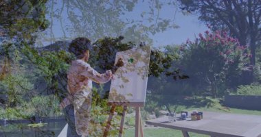 Çalı çırpıyı yeşil kavanoza daldıran kadın sanatçı tuval bina kompozisyonu üzerinde yeşil darbeler yaratıyor. Yaratıcılık, doğa, pleinair, sanatçılık, dinginlik, hobi, manzara