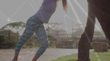 Park yoluna geri çekilip ağaca yaslanan ve baldır kaslarını esneten bir kadın sporcu. Spor, açık hava, esneklik, sağlık, doğa, spor, etkinlik