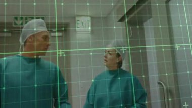 Cerrah ikilisi yeşil ızgara taramasını etkinleştiriyor. Yürüme koridoru ve prosedürden önce eldivenleri inceliyor. Tıbbi, sağlık, klinik, profesyonellik, teknoloji, tanı, takım çalışması