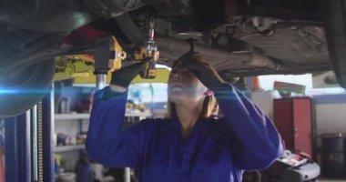 Teknisyenler arabanın altındaki sarı ingiliz anahtarına uzanıyor, soketi hizalayıp cıvatayı gevşetiyor. Tamirci, endüstriyel, makine, güvenlik, bakım, onarım, dayanıklı