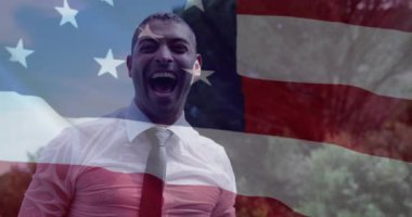 Pazarlamacı açık havada bayrağa tepki veriyor ve ulusal gururu kutlayan kollarını havaya kaldırıyor. Vatanseverlik, kutlama, açık hava, şen şakrak, güçlü doğa.