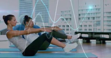 Arkadaşlar mavi paspaslarda bükük bacakları kaldırıyor, geriye yaslanıyor ve çekirdek egzersizlerini dalga boyu grafikleriyle senkronize ediyorlar. Spor, egzersiz, sağlık, güç, egzersiz, sağlık, hareket
